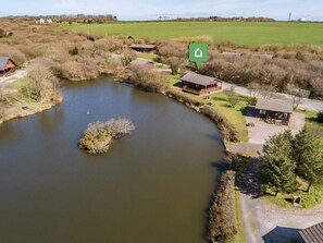 Une propriété située au bord de la rivière, comprenant un étang, des cabanes en bois et un champ d’herbe.