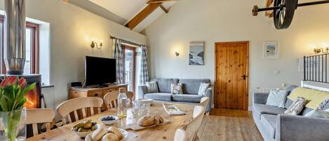 Un salon chaleureux avec une table en bois mise pour le repas, un canapé et un téléviseur.