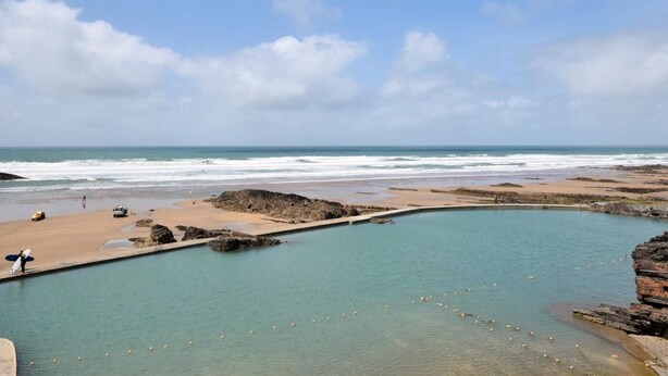 Eine Küstenlandschaft mit blauem Himmel, Strand und Schwimmbad.