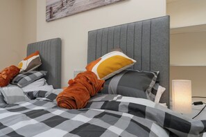 A hotel room with a bed, a headboard, and a bedside lamp. - The Porterhouse - Residence I (Winchester)