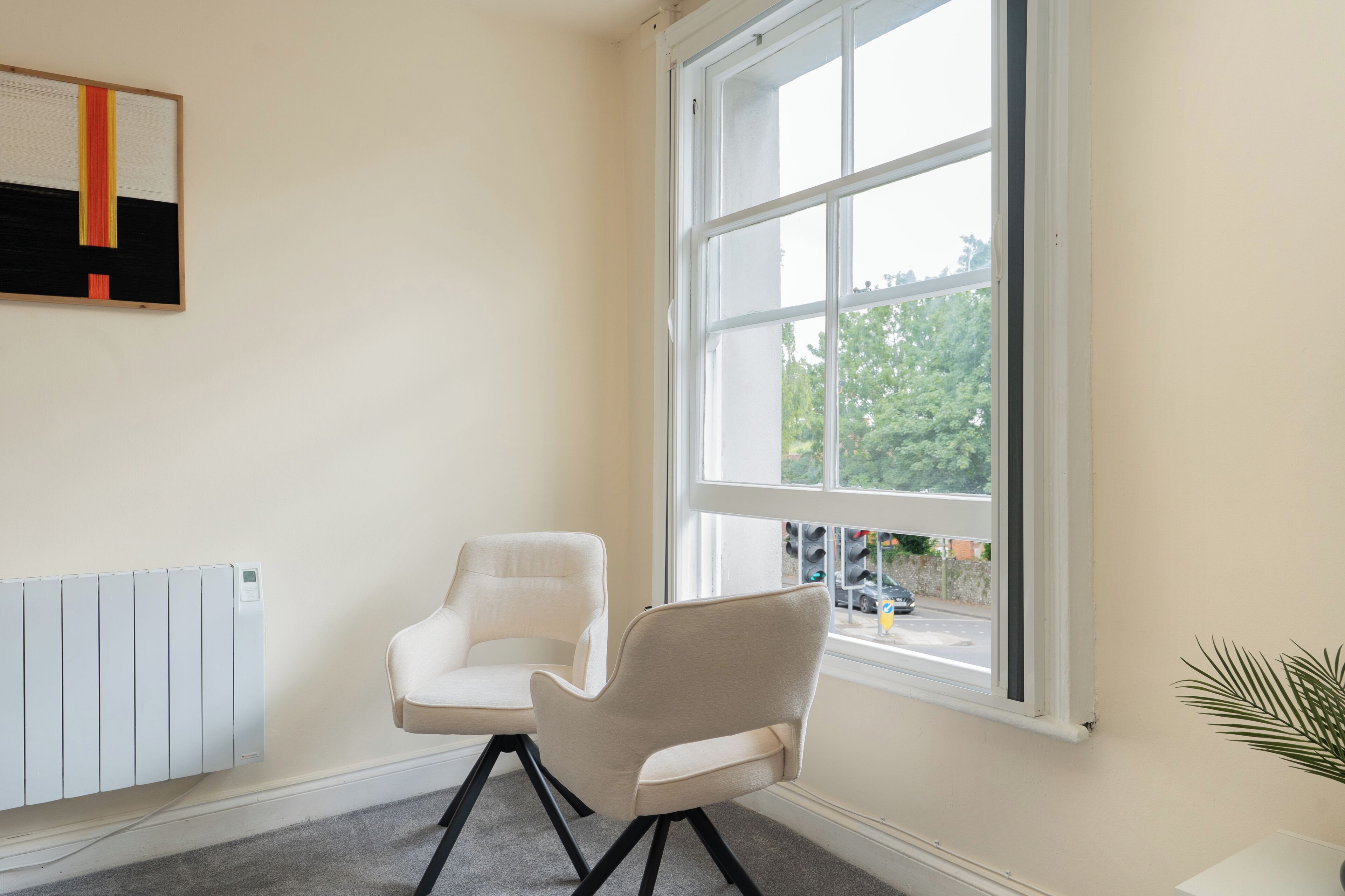A room with a large window, a radiator, and two chairs.