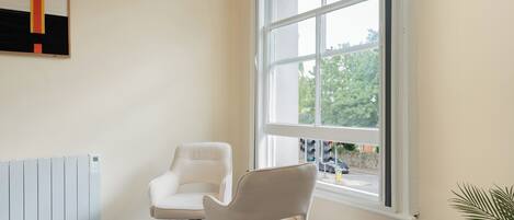 A room with a large window, a radiator, and two chairs.