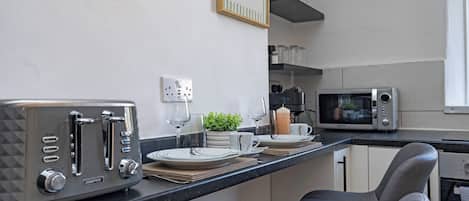 Una cocina moderna con tostadora integrada, microondas y cafetera.