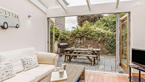 Eine gemütliche Terrasse mit einer Couch, einem Tisch und einem Fernseher.