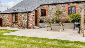 A stone building with a tiled roof, a wooden door, and a picnic table in the yard. - 1 Bed in Holsworthy (oc-gblue) (Holsworthy Hamlets)