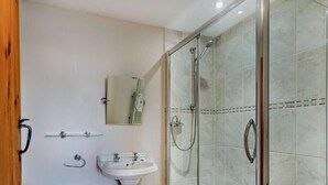 Een badkamer met een wastafel op voetstuk, een douchecabine van glas en een spiegel.