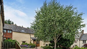 A courtyard with a large tree, a stone staircase, and a building with a sloped roof. - 2 Bed in Ilfracombe (oc-maltc) (West Down)