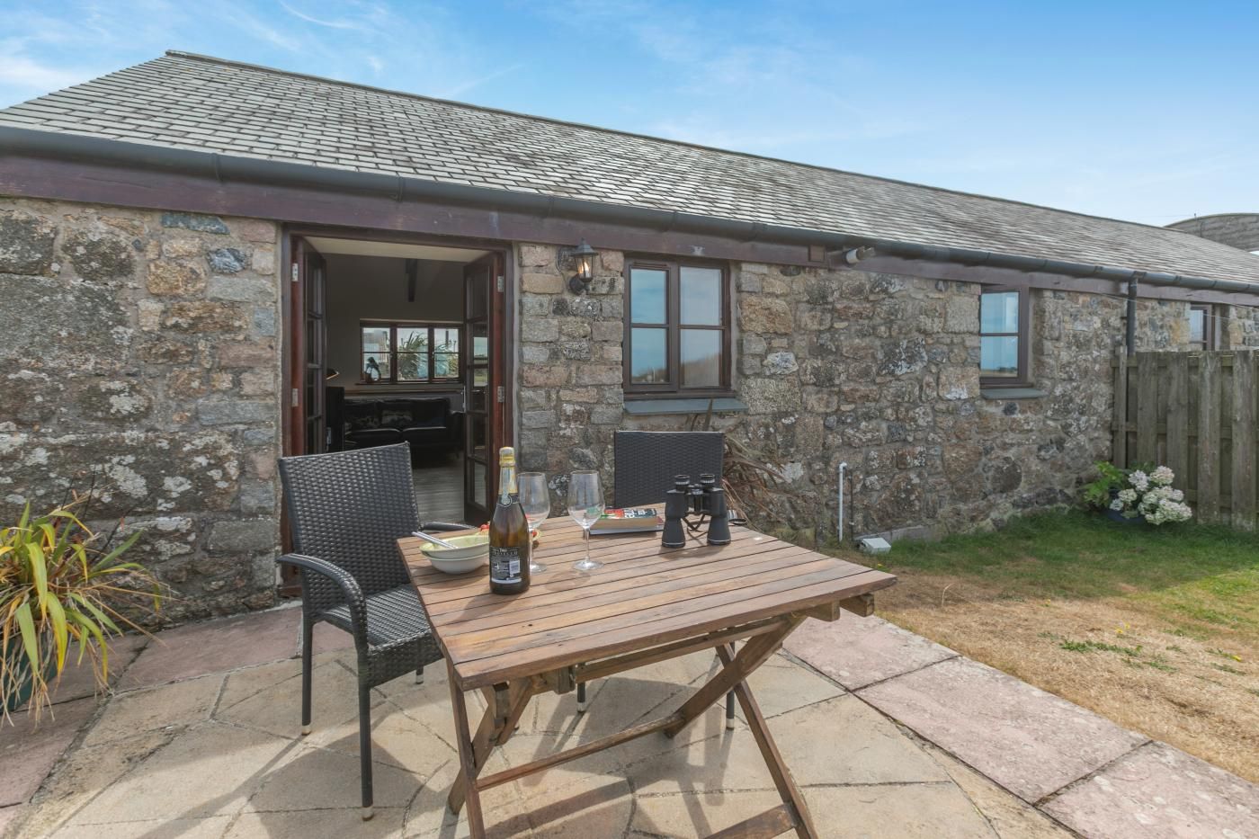 A stone building with a patio area featuring a table, chairs, and outdoor seating.