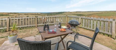 Un patio al aire libre con una mesa lista para comer, una parrilla y vistas al campo.
