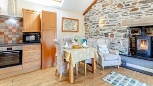 Une cuisine chaleureuse avec des meubles en bois, un mur en pierre et une cheminée.