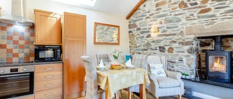 A cozy kitchen with wooden cabinets, a stone wall, and a fireplace.