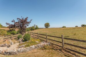 Un paysage rural avec une clôture en bois, un arbre et un mur de pierres.