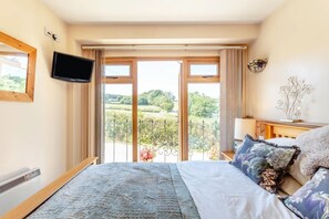 A bedroom with a bed, a television, a window with a view of greenery, and a small table with a lamp. - 1 Bed in Tavistock (oc-colch) (Gulworthy)