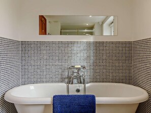 A bathroom with a white bathtub, a blue towel, and a mirror above the tub. - 1 Bed in Sidmouth (oc-hayes) (Harpford)