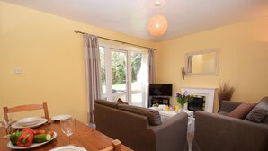 Ein Wohnzimmer mit Sofa, einem Esstisch mit Tellern und Besteck, einem Fernseher und einem Kamin.