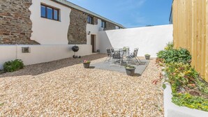 Eine Terrasse mit Grill, Sitzgelegenheit im Freien und einem Gartenbereich.