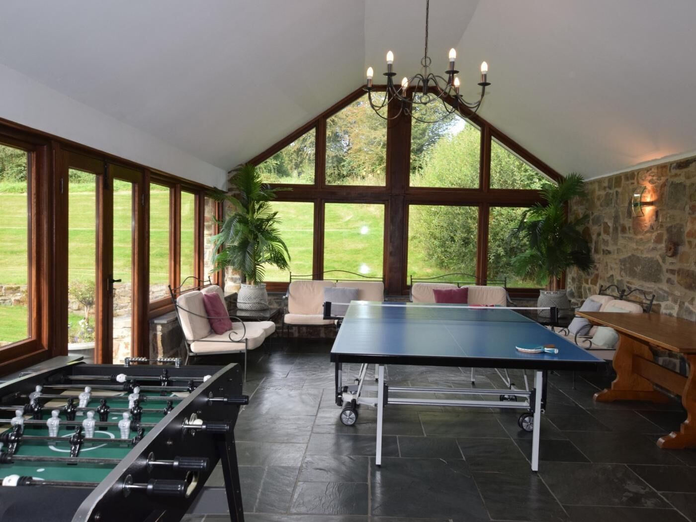 Een kamer met een tafelvoetbaltafel, een pingpongtafel en een zithoek met uitzicht op het omliggende landschap.