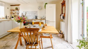 Una cocina moderna con armarios blancos, una mesa de comedor de madera y un ventanal grande.