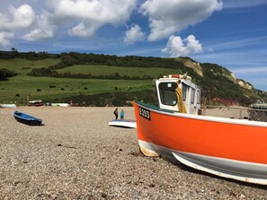 A beach with boats, a grassy hill, and a clear sky. - 3 Bed in Exeter (oc-harri) (Talaton)