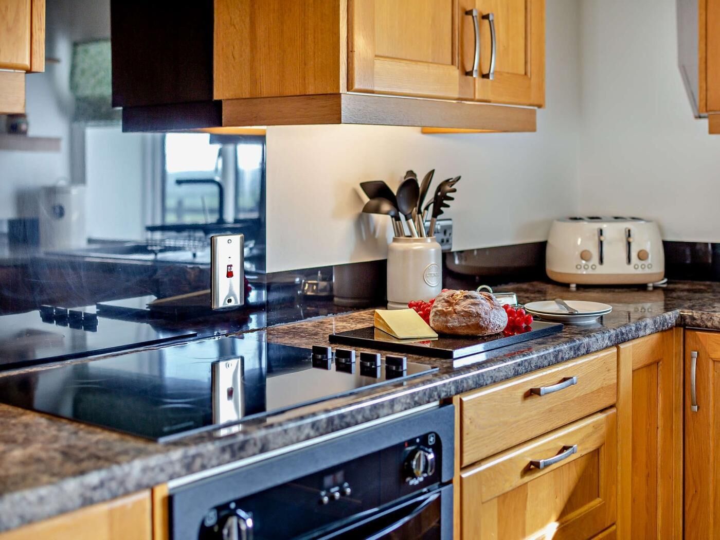 A modern kitchen with wooden cabinets, a black stovetop, a toaster, and a coffee maker.