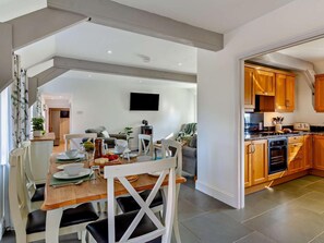 Eine moderne Küche mit Holzausstattung, ein Essbereich mit Tisch und Stühlen sowie ein Wohnzimmer mit Sofa und Kamin.