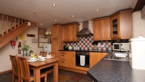 Una cucina con mobili in legno, un piano di lavoro nero, un fornello, un forno a microonde e un'area pranzo con tavolo e sedie.