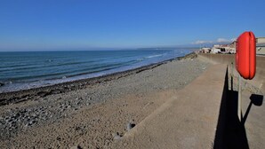 Uma praia com uma torre salva-vidas e um calçadão de concreto.