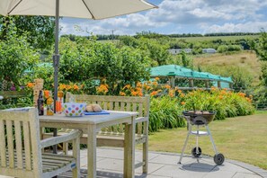 An outdoor patio with a table, chairs, a grill, and a bench. - 2 Bed in Bude (oc-00952) (Launcells)