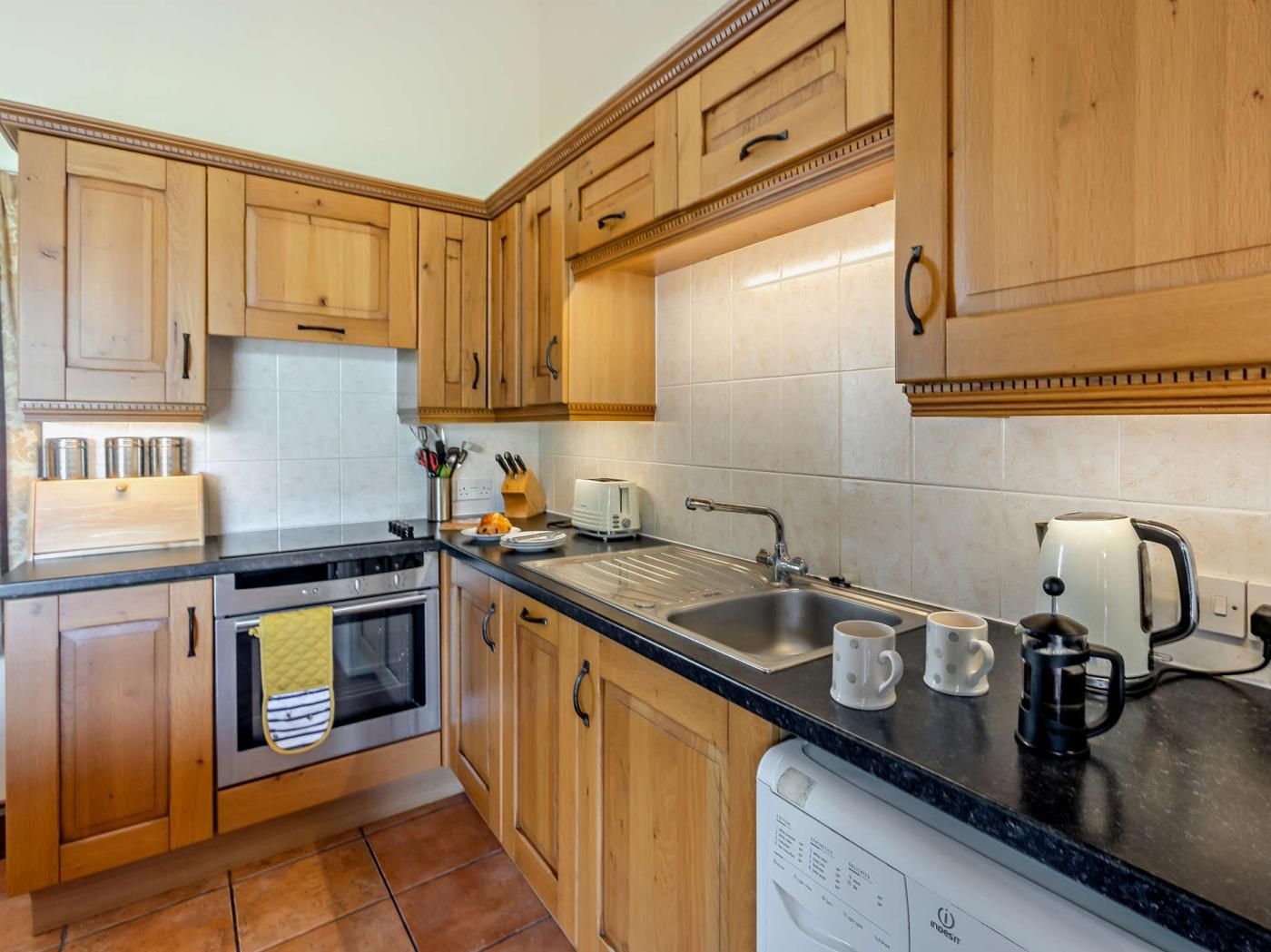 A kitchen with wooden cabinets, a stainless steel sink, a coffee maker, and a dishwasher.