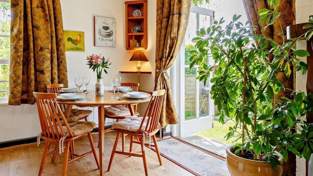 A dining area with wooden chairs, a table set for four, and a potted plant. - 2 Bed in St Austell (oc-lanyo) (Coombe)