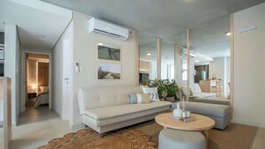 A modern living room with a sofa, a round coffee table, and a large mirror. - Corporate Stays Insignia City - B52 (Asunción)