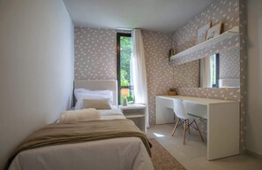 Un dormitorio con cama, escritorio y ventana.