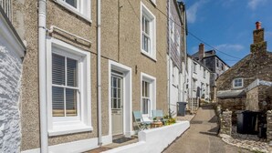 En smal gata med traditionella hus byggda av sten, vita fönsterramar och en klar himmel.