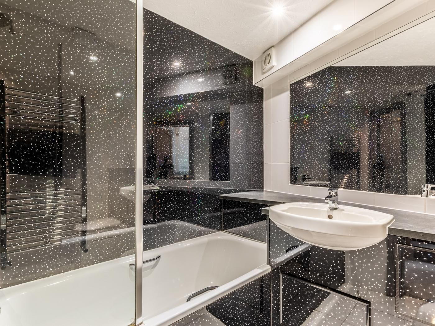 A modern bathroom with a bathtub, a large mirror, and a sink.