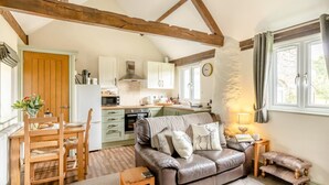 A cozy living room with a sofa, a dining table, and a kitchen in the background. - 1 Bed in Taunton (oc-oldli) (Wiveliscombe)