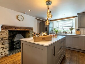 Una cocina con chimenea de piedra, una isla de madera y una ventana con persianas.