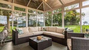Un invernadero con un sofá modular, muebles de mimbre y una mesa de centro.