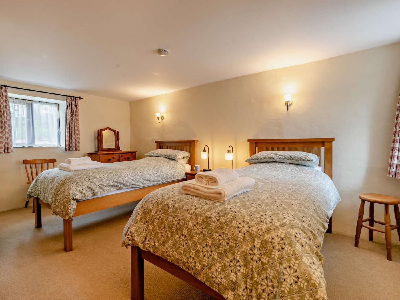 Une chambre avec deux lits, une commode, un miroir et des lampes de chevet.