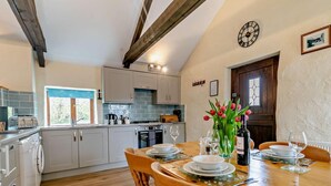 A kitchen with a dining area, wooden beams, a clock, and a window. - 2 Bed in Camborne (oc-oldmm) (Camborne)