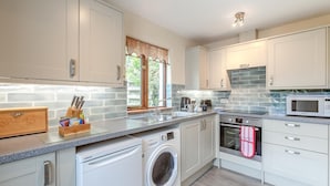 Une cuisine moderne équipée d’un lave-linge, d’un four à micro-ondes et d’un coffre à pain en bois.