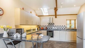 A modern kitchen with a central island, stainless steel appliances, and a checkered backsplash. - 3 Bed in Callington (oc-mbarn) (Linkinhorne)