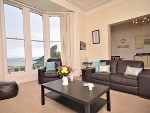 A living room with two sofas, a coffee table, and a view of the sea.