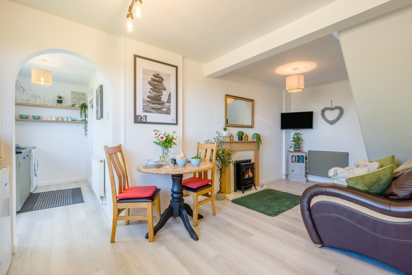 A modern living room with a fireplace, a dining area with a table and chairs, and a cozy seating area with a sofa.