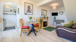 Un salon moderne avec une cheminée, un coin repas avec une table et des chaises, et un espace salon confortable avec un canapé.