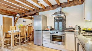 A modern kitchen with wooden beams, a stainless steel refrigerator, a built-in oven, and a granite countertop. - 3 Bed in Camelford (oc-pendw) (Davidstow)