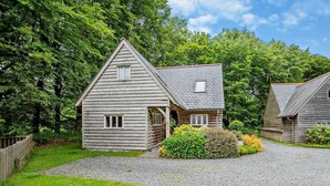 A wooden cabin with a gravel driveway, surrounded by lush greenery. - 3 Bed in Camelford (oc-pendw) (Davidstow)