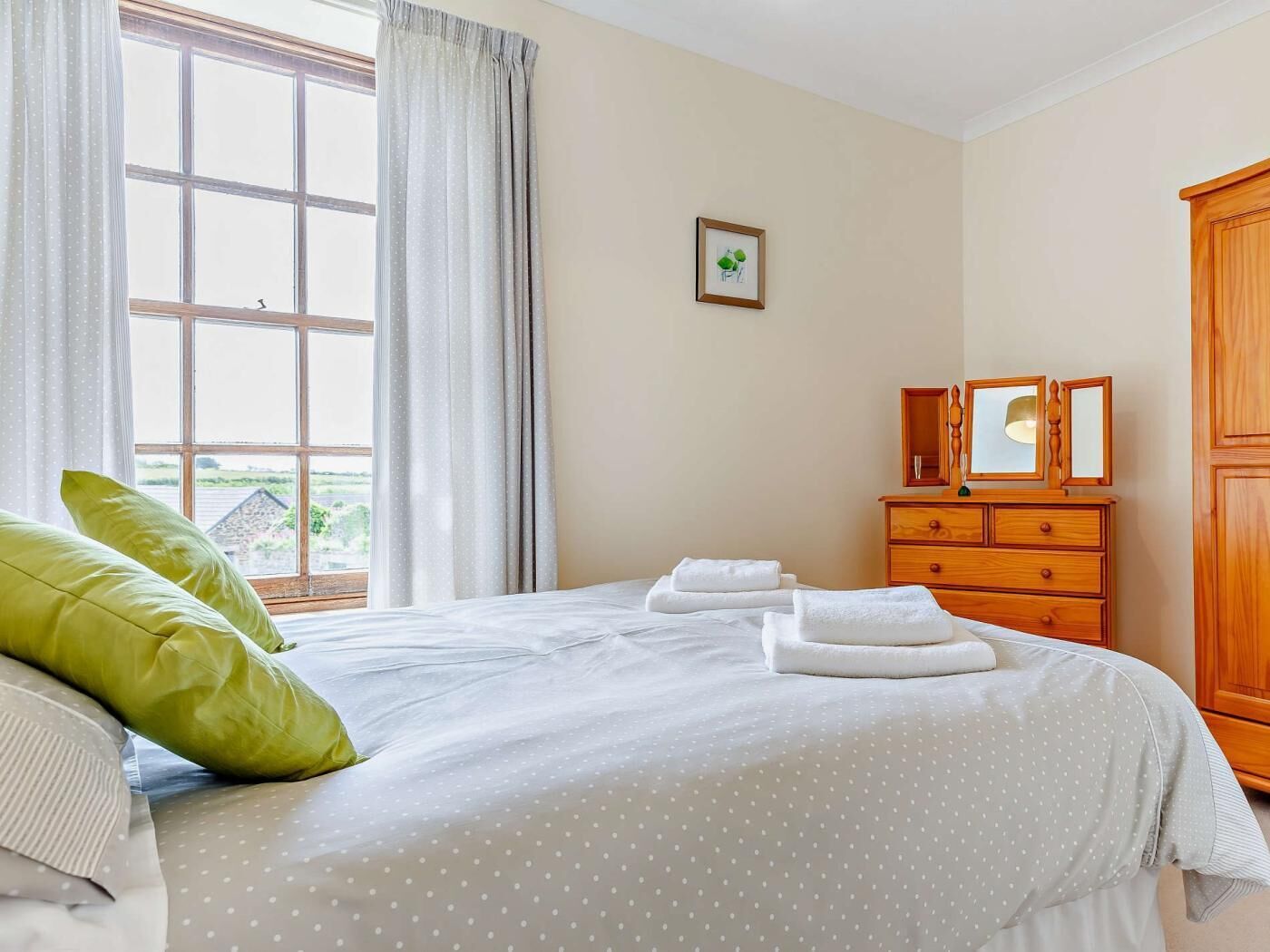 Une chambre à coucher avec un lit, une commode, une fenêtre et un tableau au mur.
