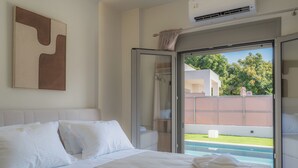 A hotel room with a bed, a glass door leading to a balcony, and a view of a swimming pool.