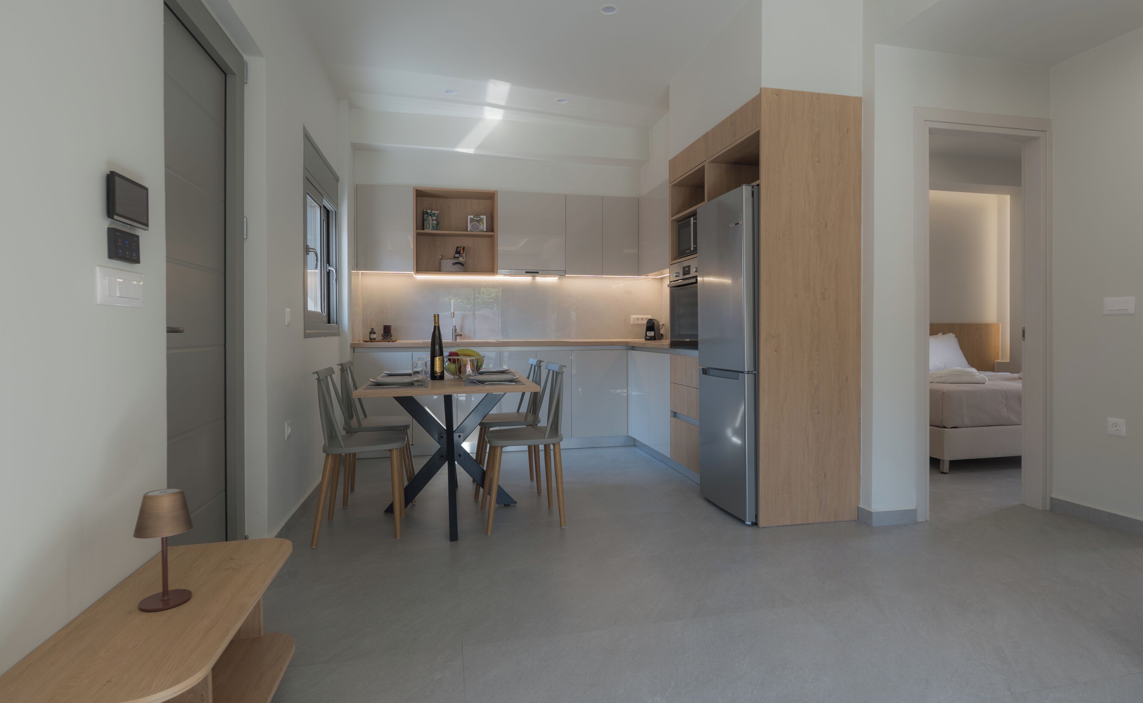 Eine moderne Küche mit Essbereich, ein Kühlschrank und ein Bett im angrenzenden Zimmer.