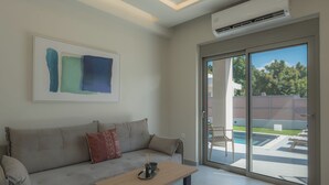 A modern living room with a sofa, a coffee table, and a large sliding glass door leading to an outdoor area.
